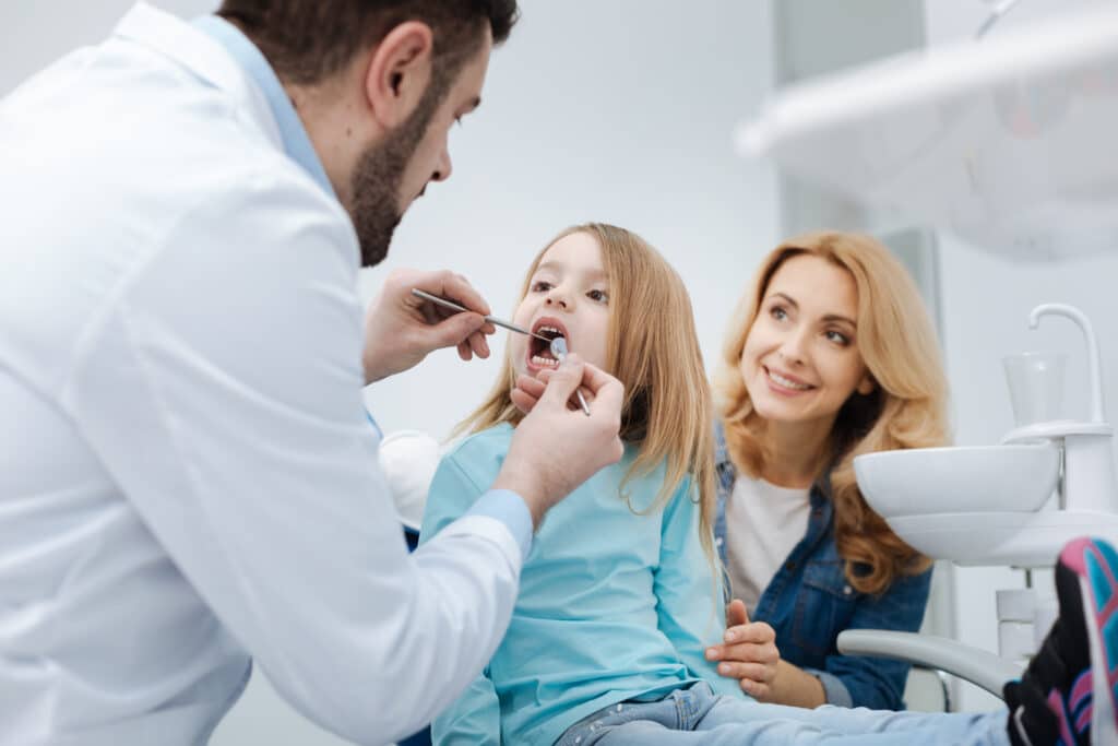 Dentist near me Kansas City performing dental examination with nurse and doctor assisting
